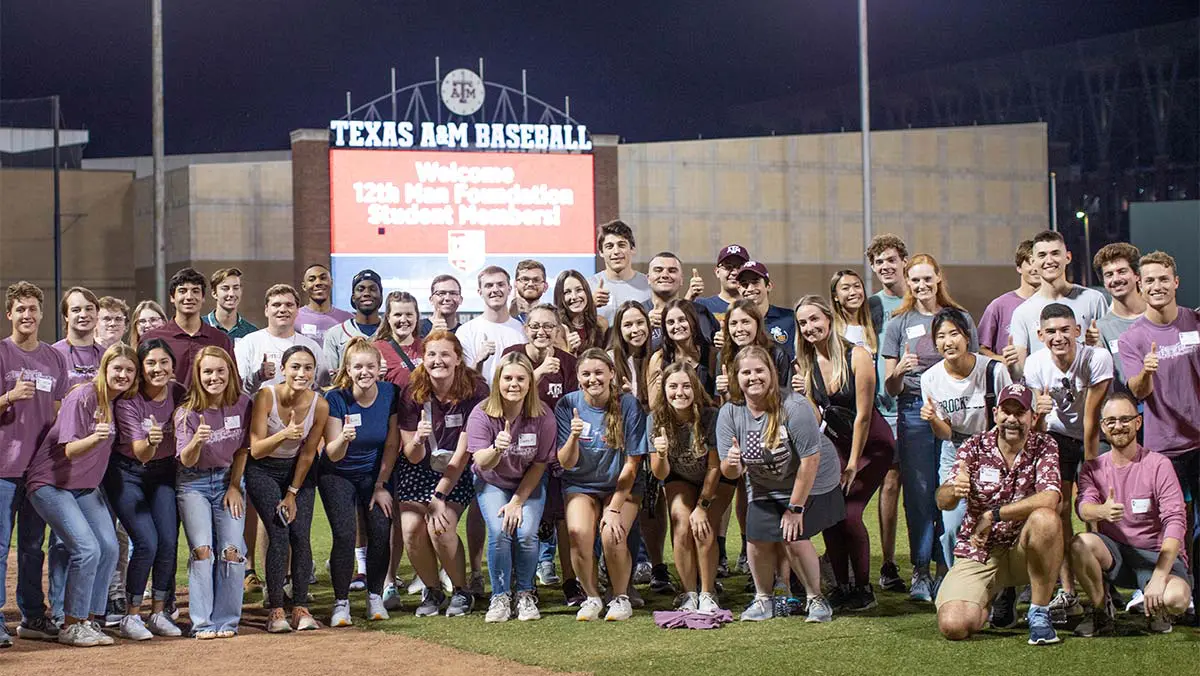 group photo in front of baseball park sign