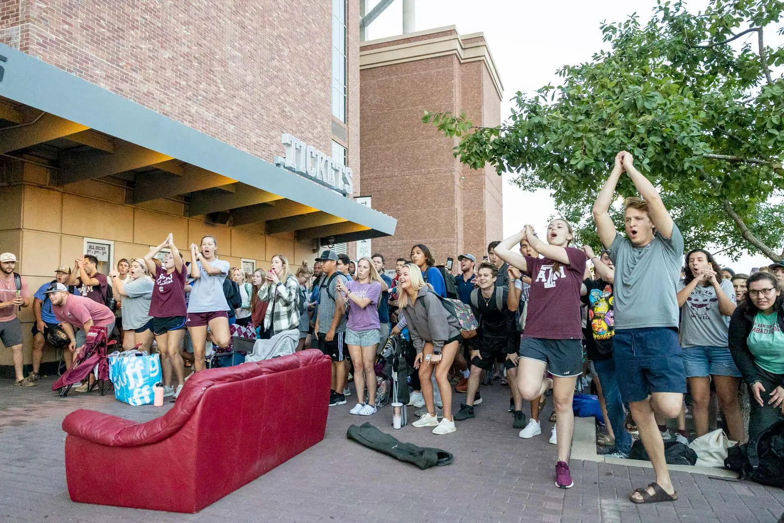 People outside of the stadium around a red couch and cheering